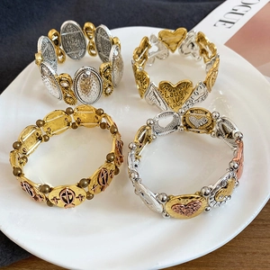 Detail view of 4-piece elastic bracelets set with heart and cross charms in a ceramic bowl