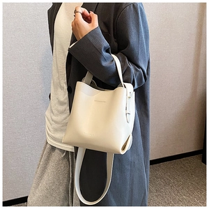 Lifestyle shot showing the cream white leather bucket bag size and fit on a female model