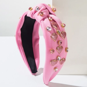 Detail eines rosa geknoteten Haarreifens mit Glitzerherzen und funkelnden Straßsteinen