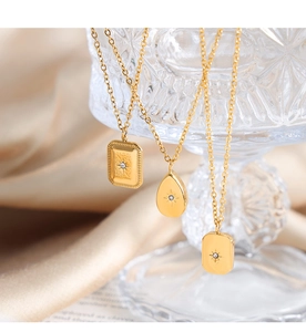 Detail of vintage 18K gold geometric pendants with starburst engraving and zircon inlay