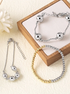 Detail of beaded and textured chain bracelets in gold and silver plating with lobster clasp