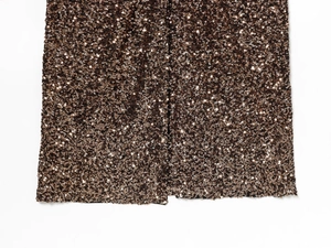 Detail of sequined dress showing brown bronze fabric texture and a side slit hemline