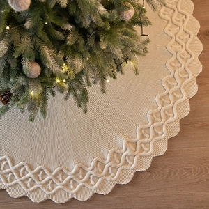 Knitted off-white Christmas tree skirt with cable weave pattern and scalloped edges
