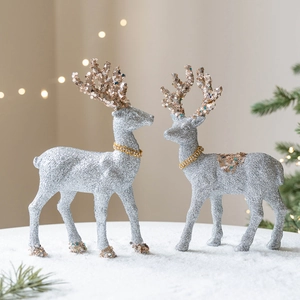 Silver Christmas reindeer figurines with gold glitter accents on snowy base