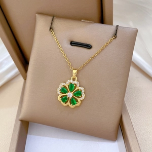 Detailed close-up of a gold-plated flower pendant with green gems on a luxury jewelry box