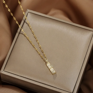 Detailed shot of golden bamboo pendant with rhinestones on brown silk fabric background