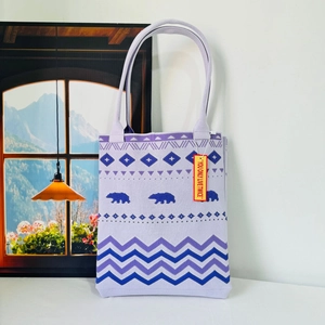Detailed view of purple knitted tote bag showing bear pattern and geometric wave texture