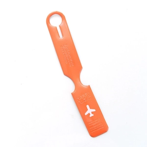 Macro shot of orange faux leather luggage tag featuring embossed plane icon and flight safety text