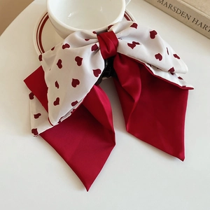 Détail de la pince à cheveux avec nœud en tissu, motif cœur rouge et longs rubans