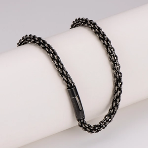 Retro black stainless steel woven chain necklace with cylindrical clasp on white pedestal