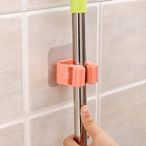 Orange wall-mounted mop holder showing non-drill installation on tile bathroom walls