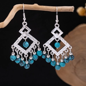 Detailed macro view of bohemian tassel earrings with turquoise beads and retro silver finish