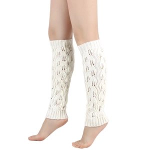 Detail of cream white cable knit leg warmers featuring intricate leaf patterns and ribbed cuffs