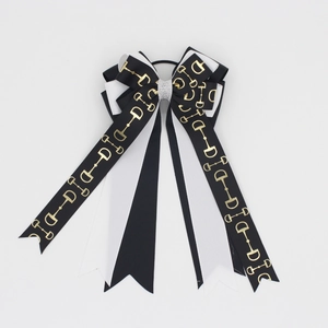 Close-up of equestrian bow hair tie featuring gold bit chain print on ribbon
