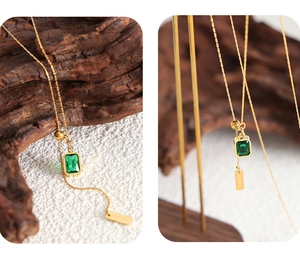 Detail of gold twisted chain necklace with green gemstone and BABY engraved tag