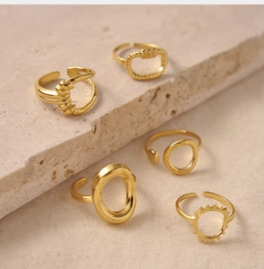 Detail shot of five textured 18K gold plated twisted rings on stone and fabric