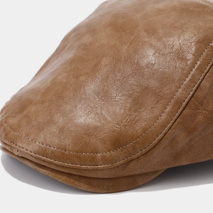 Close-up of brown leather beret hat showing premium lychee grain texture and stitching