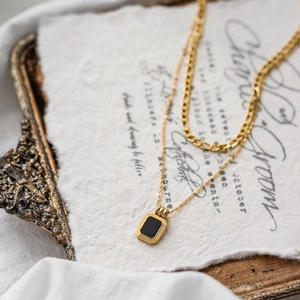 Macro detail of double-layer titanium necklace with rectangular black enamel pendant