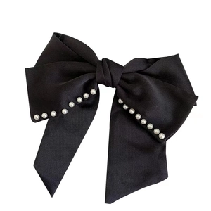 Große elegante schwarze Satin-Haarschleife mit weißen Perlen am Rand auf weißem Hintergrund