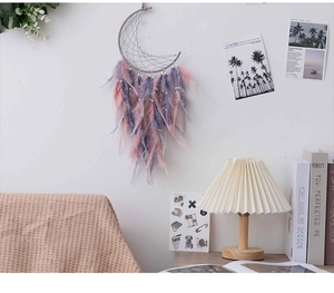 Detail of moon-shaped dream catcher with pink and purple feathers in a cozy room