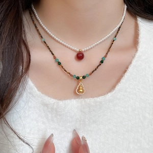 Close-up of layered necklace with natural tiger eye beads and golden gourd zircon pendant