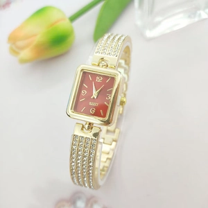 Elegant gold square watch with red dial and rhinestone-set metal strap on a floral backdrop