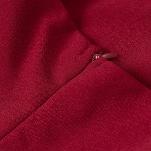 Detailed view of deep red fabric texture and smooth invisible zipper closure on the dress