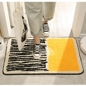 Detail of plush tufted bath mat with black stripes and yellow contrast on wood floor