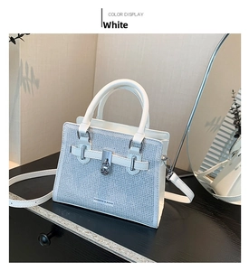 Detail view of white crossbody bag featuring sparkling rhinestone surface and round clasp