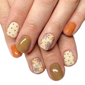 Glossy autumn press-on nails featuring maple leaf designs and mocha polka dot patterns