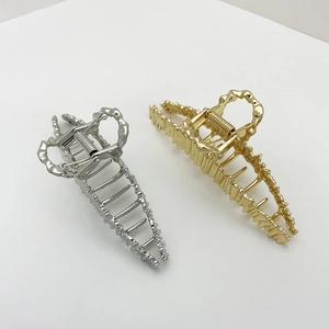 Detailed view of silver and gold irregular lava textured metal hair claw clips on white