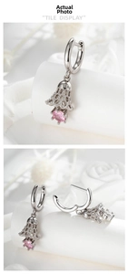 Detailed view of silver hoop earrings with hollow bell pendants and pink gemstones