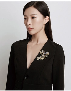 Detailed view of a gold-plated bow brooch with sparkling rhinestones on a black blazer