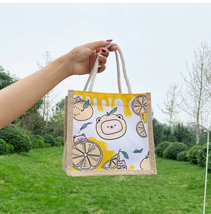 Detail of canvas tote bag featuring cartoon bear and lemon prints with jute rope handles