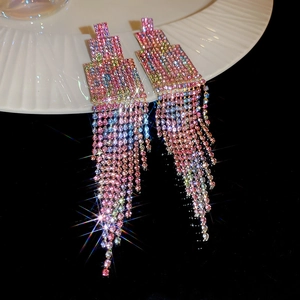 Gros plan de boucles d'oreilles franges en strass à dégradé coloré sur une assiette blanche