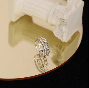 Macro shot of double-layered silver ring with chain links and zircon stones on gold mirror