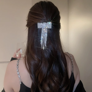 Gros plan d'une barrette nœud en strass avec de longs glands sur cheveux bouclés