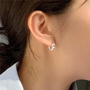 Close-up of minimalist polished silver bean studs worn on the earlobe for a chic look