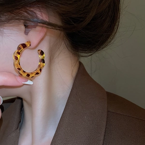 Close-up of leopard print resin C-shaped hoop earrings with wavy edges for a retro style