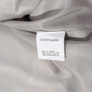 Detailed close-up of garment care label showing 100% polyester fabric and washing symbols