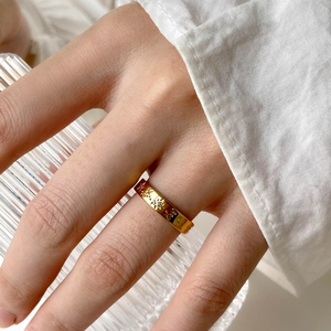 Detail of gold star and moon embossed ring with zircon on person holding a glass cup