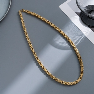 Detail of 5mm gold Byzantine titanium steel chain with lobster clasp on grey background