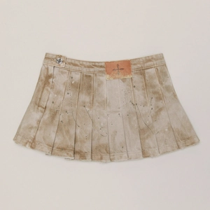 Détail d'une jupe plissée vintage en denim avec finition tie-dye et boutons croix