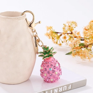 Detail of pink crystal pineapple keychain with gold lobster clasp on white vase