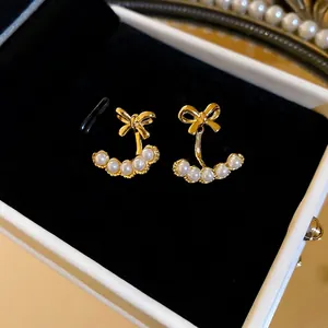 Elegant 18k gold plated bow earrings featuring five dangling white pearls on black velvet