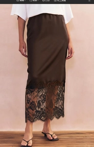 Detailed view of brown satin midi skirt featuring black lace trim hemline and smooth texture