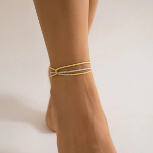 Close-up of triple-layered gold and silver interlaced ankle chain on model