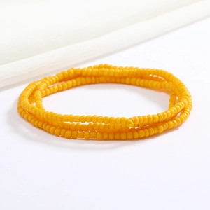 Close-up of a double-layered yellow seed bead waist chain on a soft white fabric background