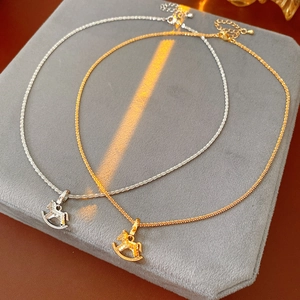 Dettaglio dei ciondoli a forma di cavallo a dondolo in oro e argento scintillanti