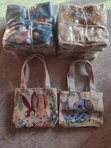 Detailed view of canvas tote bags featuring elephant and rabbit embroidery patterns
